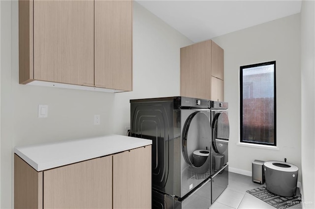 washroom with light tile patterned floors, baseboards, cabinet space, and washing machine and clothes dryer