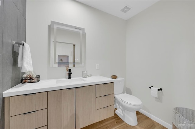 bathroom featuring visible vents, wood finished floors, vanity, baseboards, and toilet