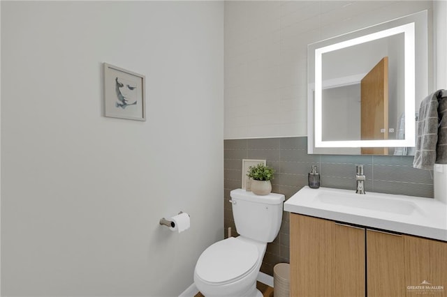 bathroom featuring vanity, toilet, and tile walls