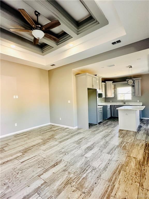 kitchen featuring appliances with stainless steel finishes, coffered ceiling, ceiling fan, a center island, and hanging light fixtures