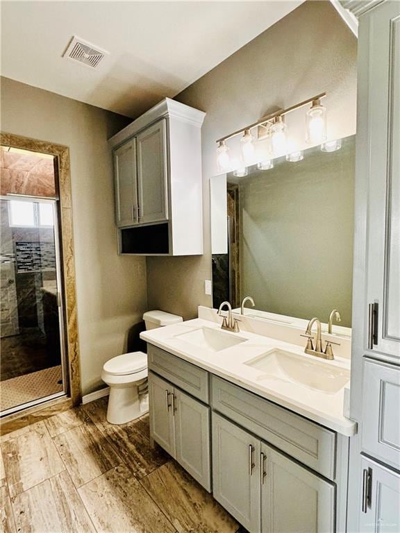 bathroom with a shower with door, vanity, and toilet