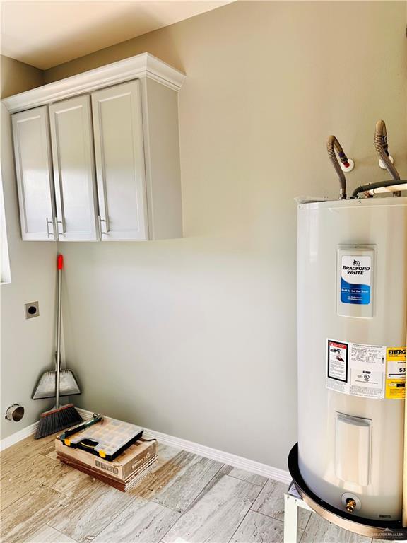 washroom with hookup for an electric dryer, cabinets, and water heater