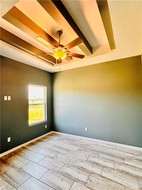 empty room with beamed ceiling, a raised ceiling, and ceiling fan