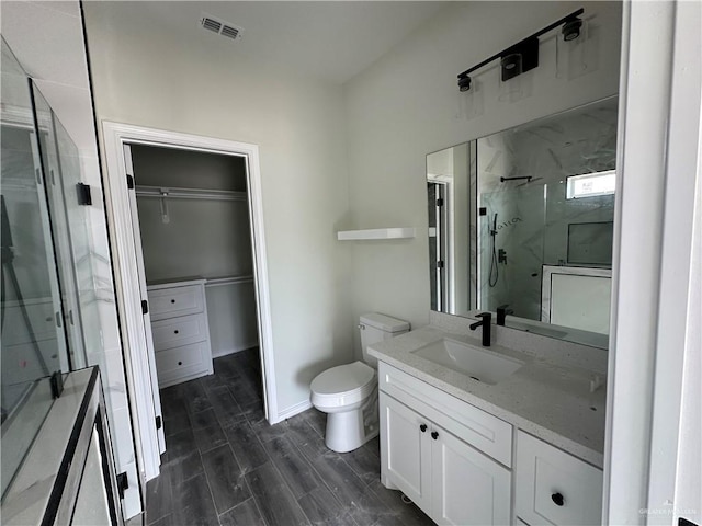 bathroom with a shower with door, vanity, and toilet