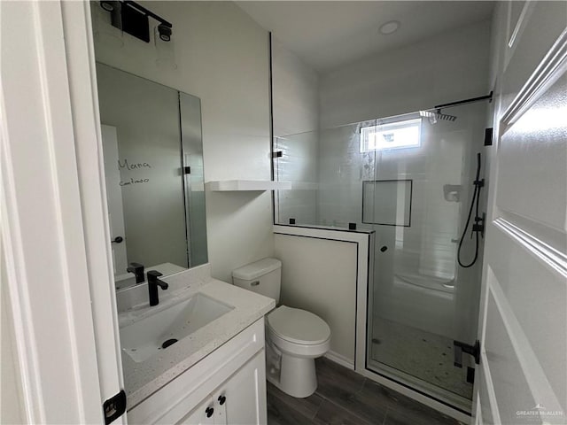 bathroom featuring vanity, wood-type flooring, an enclosed shower, and toilet