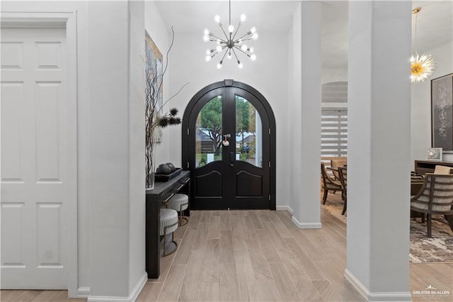 entrance foyer featuring french doors, light hardwood / wood-style flooring, and a notable chandelier