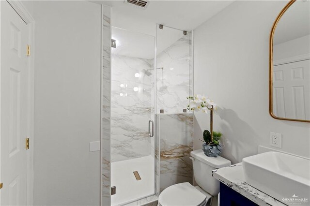 bathroom featuring vanity, toilet, and a shower with shower door