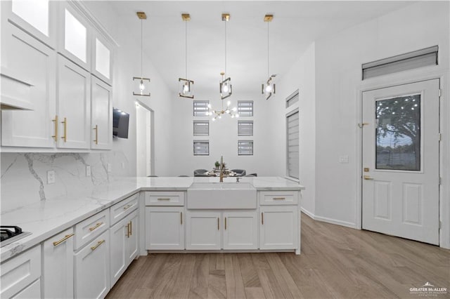 kitchen featuring kitchen peninsula, white cabinetry, and decorative light fixtures