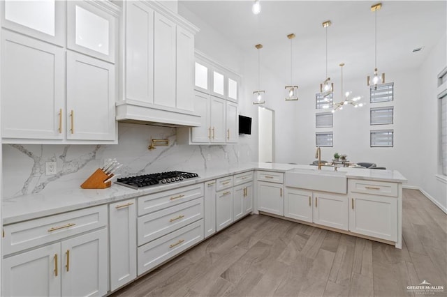 kitchen featuring sink, custom range hood, decorative light fixtures, kitchen peninsula, and stainless steel gas cooktop