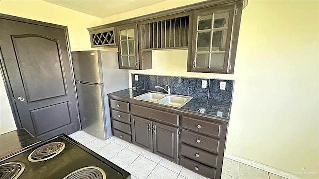 kitchen with stainless steel refrigerator, sink, black range, dark brown cabinets, and light tile patterned floors