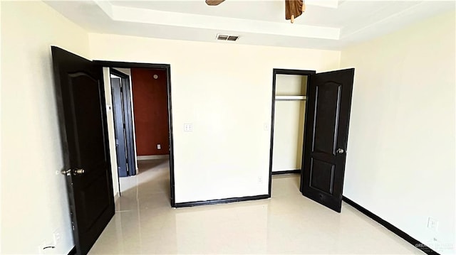 unfurnished bedroom with a tray ceiling and ceiling fan