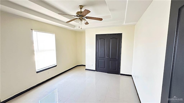 spare room with a tray ceiling and ceiling fan