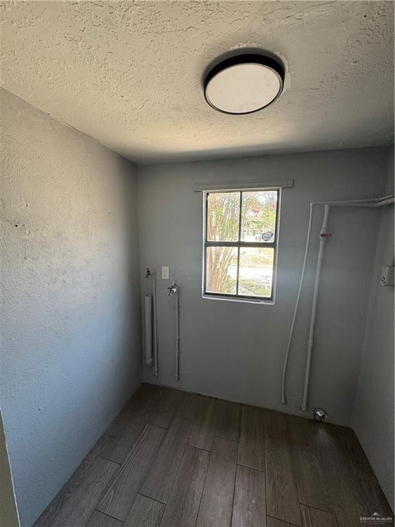 empty room with a textured ceiling and dark wood finished floors