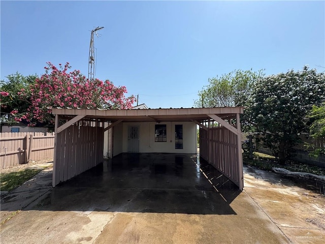 exterior space featuring an attached carport, driveway, and fence