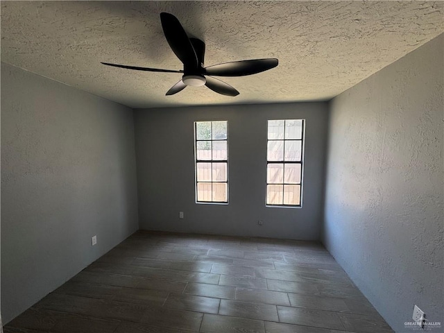 spare room with a textured wall, a textured ceiling, and ceiling fan