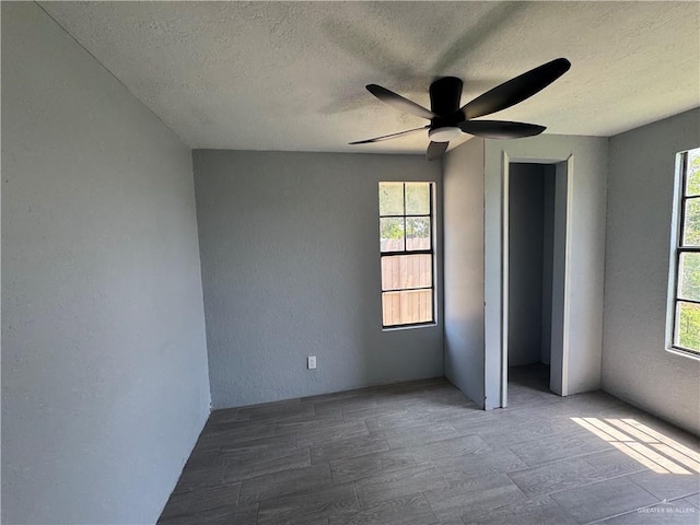 unfurnished bedroom with a textured wall, a textured ceiling, wood finished floors, and ceiling fan