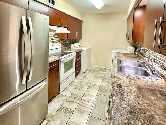 kitchen with tasteful backsplash, sink, washer and dryer, electric range, and stainless steel refrigerator