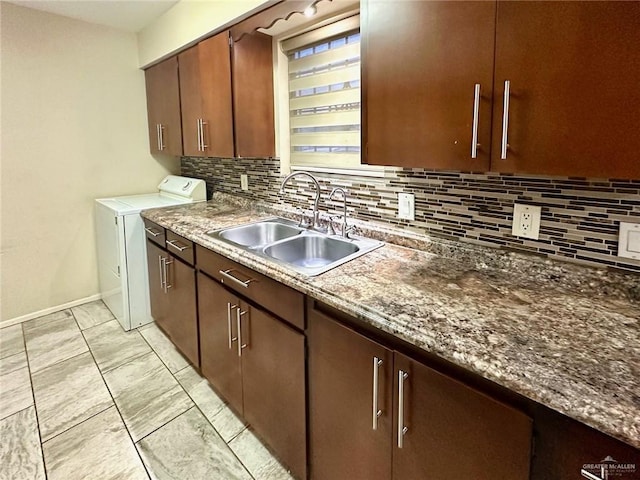 kitchen with backsplash, dark stone countertops, separate washer and dryer, and sink