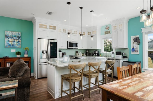 kitchen featuring appliances with stainless steel finishes, a center island, white cabinetry, and dark wood-type flooring