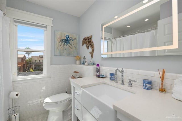 bathroom with tile patterned flooring, vanity, toilet, and tile walls