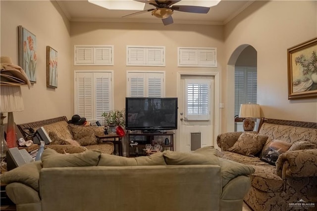 living room with crown molding, a ceiling fan, and arched walkways