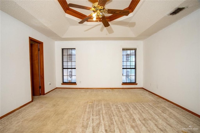 carpeted spare room with ceiling fan, a raised ceiling, and a textured ceiling