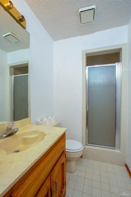 bathroom with a textured ceiling, toilet, tile patterned floors, a shower with door, and vanity