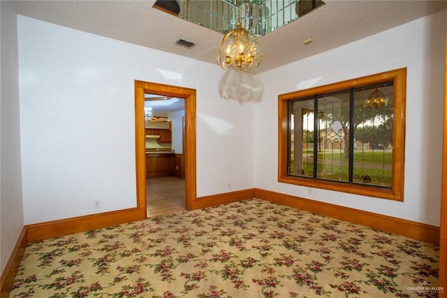 empty room with a textured ceiling and an inviting chandelier