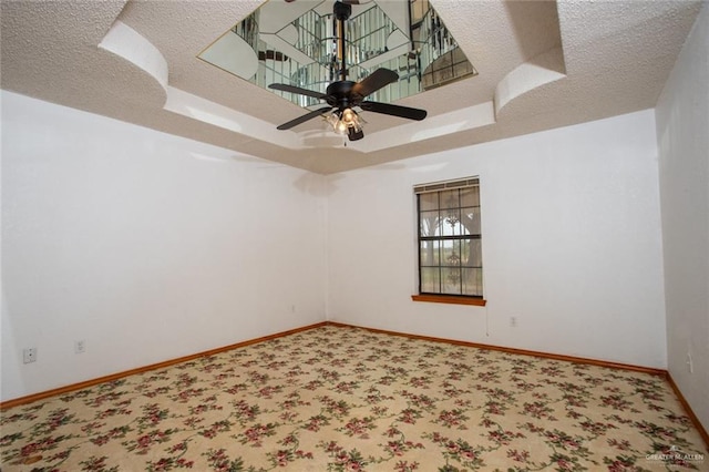 spare room featuring a raised ceiling, ceiling fan, and a textured ceiling