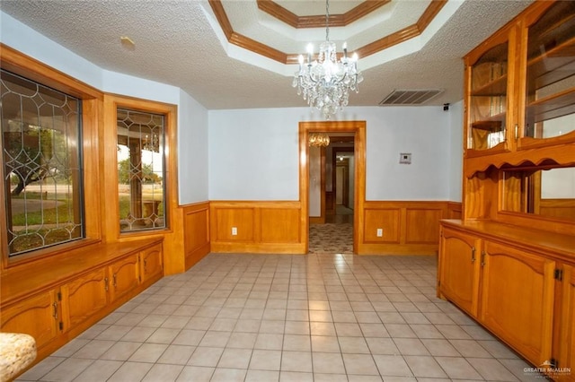 dining area with a raised ceiling, a notable chandelier, crown molding, and a textured ceiling