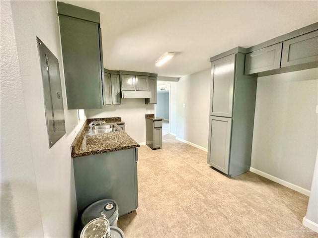 kitchen with sink, light colored carpet, and dark stone counters