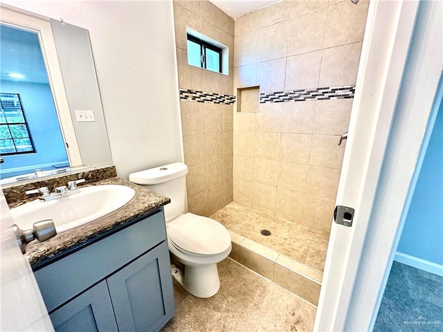 bathroom featuring plenty of natural light, vanity, toilet, and a tile shower