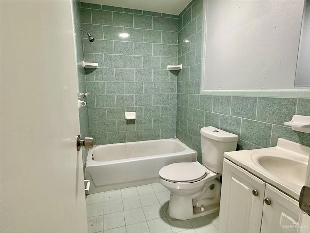 full bathroom featuring tiled shower / bath, tile walls, tile patterned flooring, vanity, and toilet