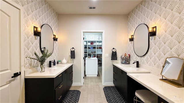 2800 Encke Rd, Mission, TX 78574 - bathroom featuring wallpapered walls, an accent wall, wood finished floors, and two vanities