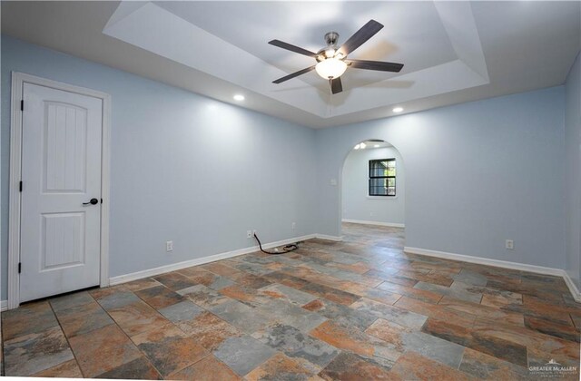 living room featuring a tray ceiling and ceiling fan