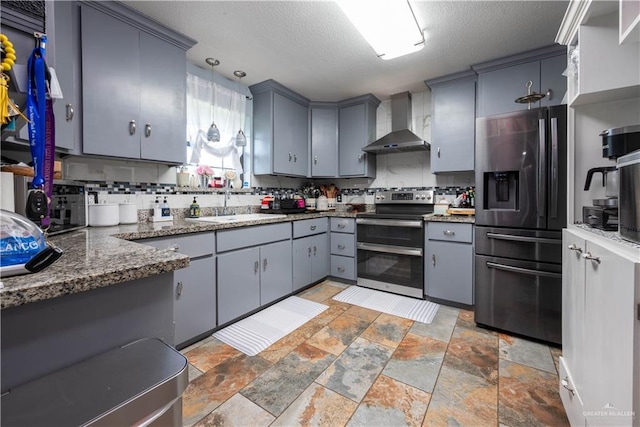 kitchen with pendant lighting, wall chimney exhaust hood, backsplash, and stainless steel appliances