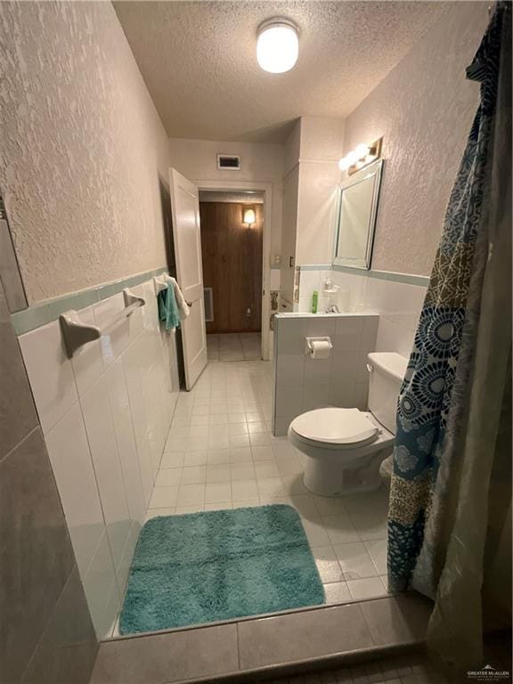 bathroom with toilet, vanity, a textured ceiling, and tile patterned floors