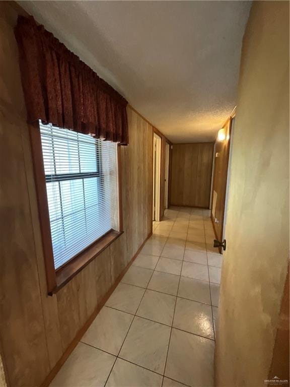 hall with light tile patterned floors and wooden walls