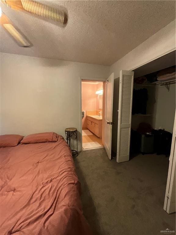 bedroom featuring carpet, sink, a textured ceiling, connected bathroom, and a closet