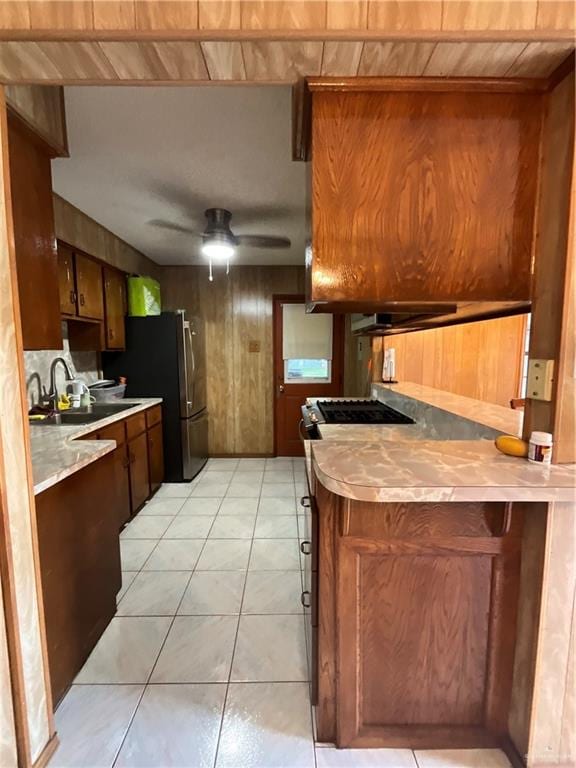 kitchen with wood ceiling, ceiling fan, sink, light tile patterned floors, and wood walls