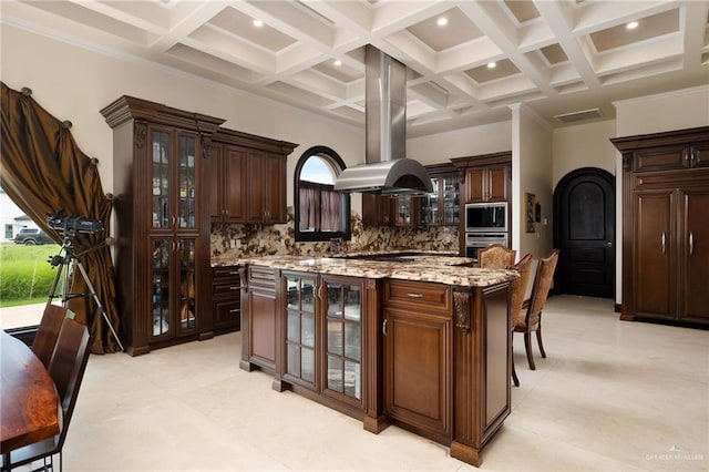 kitchen with dark brown cabinetry, decorative backsplash, a center island, and ornamental molding