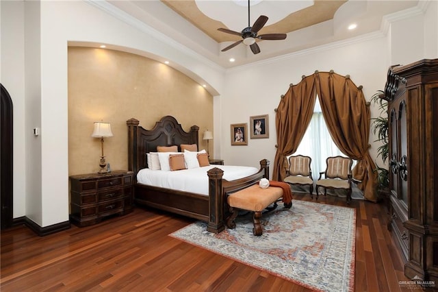 bedroom with a tray ceiling, ceiling fan, dark hardwood / wood-style flooring, and ornamental molding