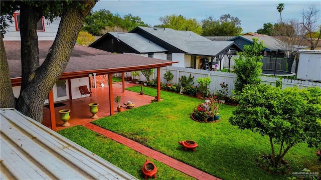 view of yard with a trampoline, a patio area, fence, and a residential view