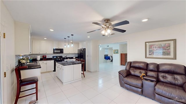 kitchen with dark countertops, open floor plan, a sink, and black appliances