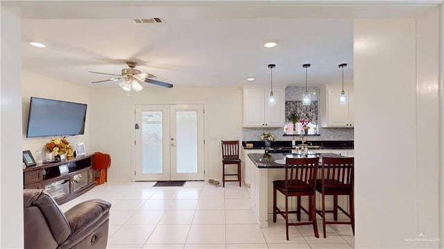 kitchen featuring visible vents, open floor plan, french doors, dark countertops, and a kitchen bar