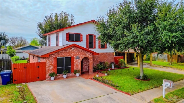 view of front of property with a gate, a front yard, fence, and brick siding