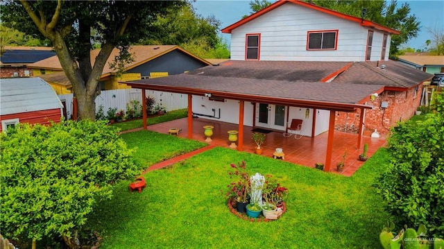 rear view of property featuring a shingled roof, a patio area, a yard, and fence