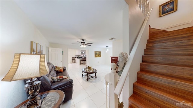 living room featuring light tile patterned floors, visible vents, stairway, and a ceiling fan