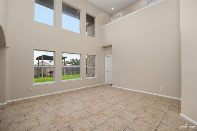 3716 Yellowhammer Ave, Mcallen, TX 78504 - empty room with healthy amount of natural light, a high ceiling, baseboards, and light tile patterned flooring