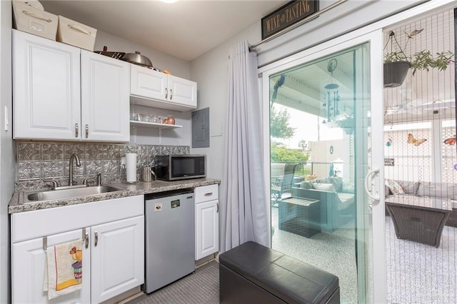 kitchen with refrigerator, decorative backsplash, stainless steel microwave, a sink, and white cabinetry